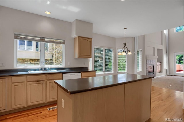 kitchen with a sink, dark countertops, white dishwasher, and light wood finished floors