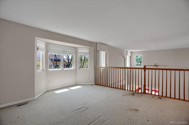 carpeted spare room with healthy amount of natural light, baseboards, and ceiling fan