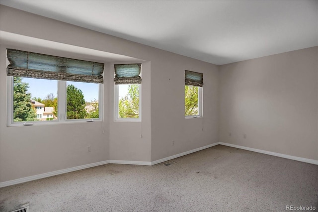 carpeted empty room featuring baseboards