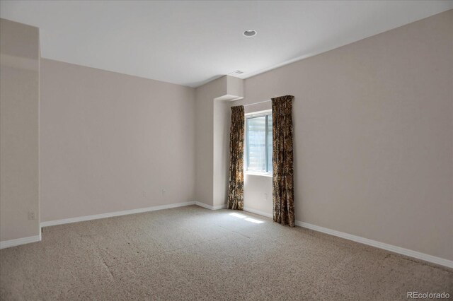 empty room featuring carpet and baseboards