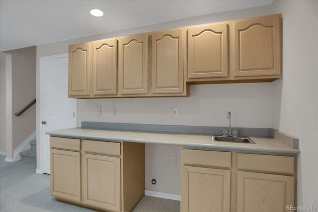 kitchen with light brown cabinets, a sink, light countertops, and baseboards