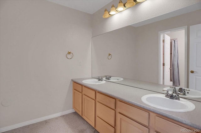 full bathroom with baseboards, double vanity, and speckled floor