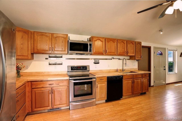 kitchen with appliances with stainless steel finishes, a sink, wood counters, and light wood finished floors