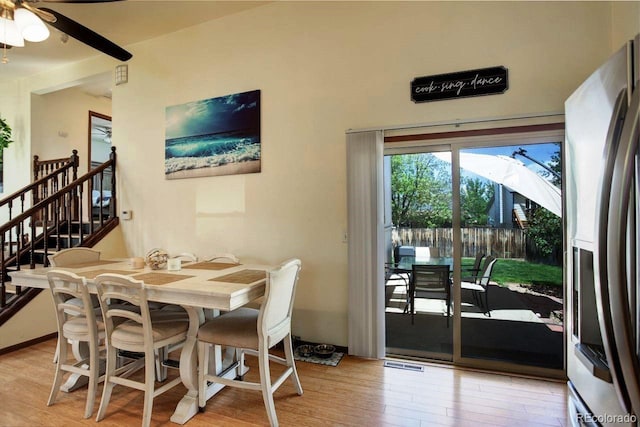 dining room with light wood-type flooring, stairway, and ceiling fan