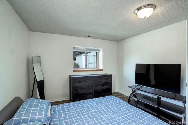bedroom featuring a textured ceiling, wood finished floors, and baseboards