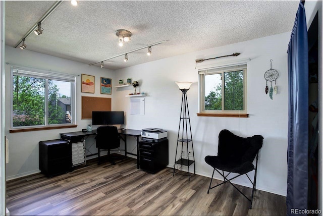 office space featuring track lighting, wood finished floors, healthy amount of natural light, and a textured ceiling