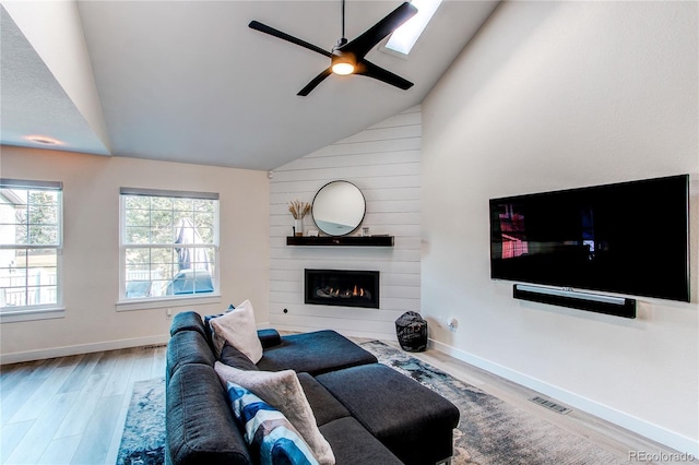 living area with ceiling fan, baseboards, wood finished floors, and a fireplace