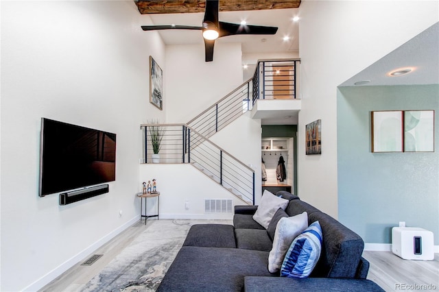 living area with visible vents, a high ceiling, baseboards, and wood finished floors