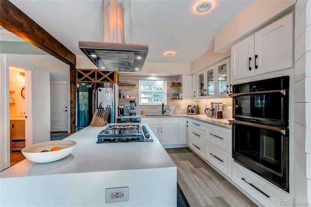 kitchen with gas cooktop, open shelves, island exhaust hood, freestanding refrigerator, and dobule oven black