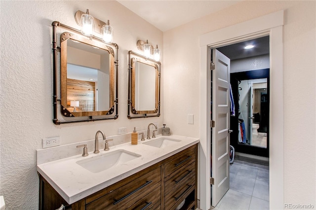 full bath featuring double vanity, tile patterned flooring, and a sink