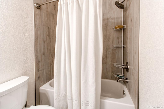 bathroom featuring toilet, a textured wall, and shower / tub combo with curtain