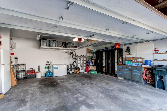 garage featuring freestanding refrigerator and a garage door opener