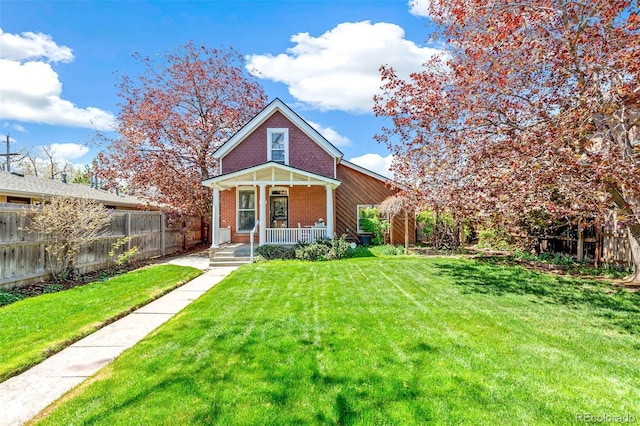 bungalow-style home with covered porch, brick siding, fence, and a front yard