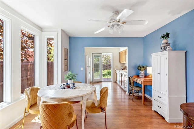 dining room with baseboards, ceiling fan, and light wood-style flooring