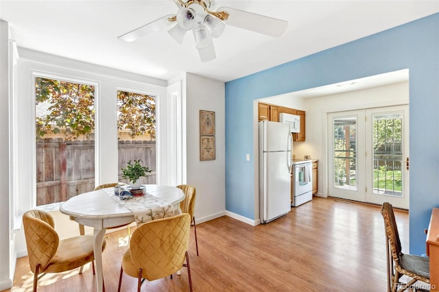 dining area with baseboards, a ceiling fan, and light wood finished floors
