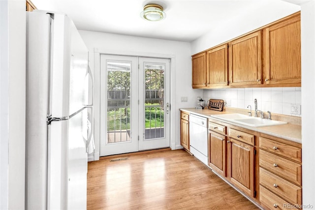 interior space with visible vents, tasteful backsplash, a sink, light countertops, and white appliances