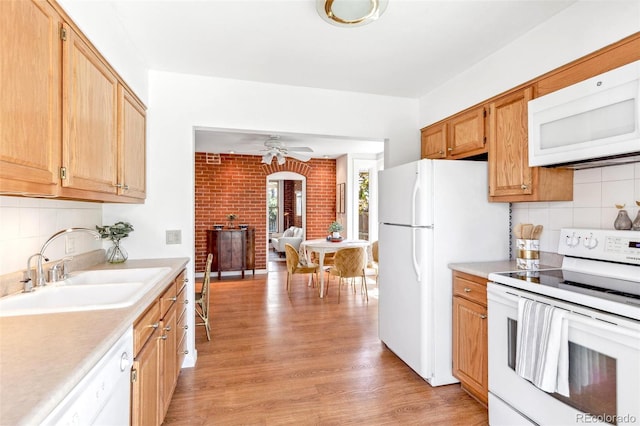 kitchen featuring a sink, light countertops, backsplash, and white appliances