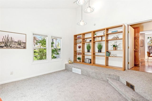 interior space with visible vents, baseboards, high vaulted ceiling, and light colored carpet