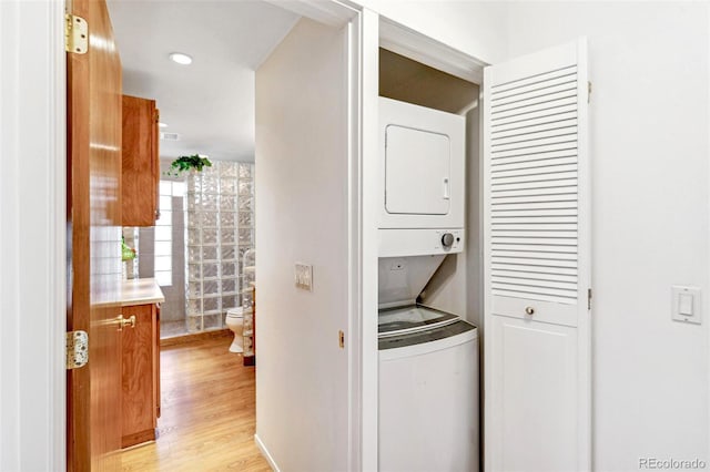 laundry area with stacked washer and dryer, laundry area, and light wood-style flooring