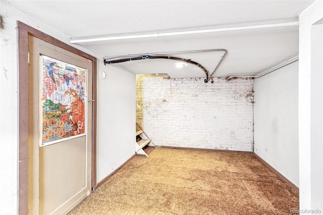 interior space featuring baseboards, carpet, and brick wall
