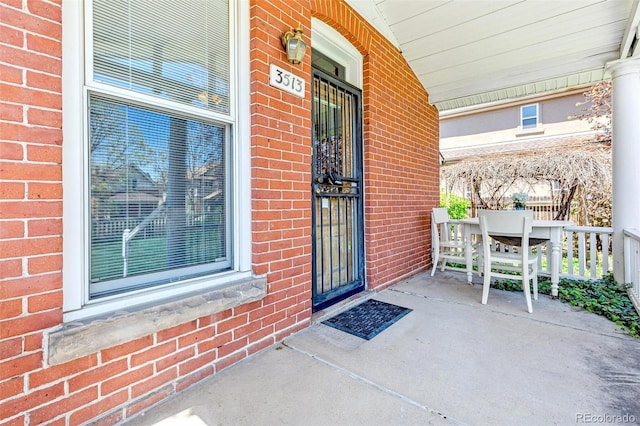 doorway to property featuring brick siding and covered porch