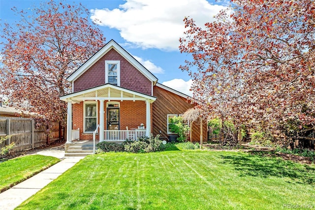 view of front facade with fence, covered porch, a front lawn, and brick siding