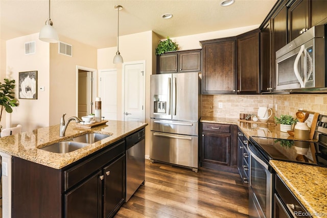 5562 W 72nd Pl, Westminster, CO 80003 - kitchen with stainless steel appliances, light stone countertops, decorative backsplash, dark wood-style floors, and a center island with sink