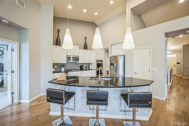 1261 W 170th Ave, Broomfield, CO 80023 - kitchen featuring appliances with stainless steel finishes, dark countertops, high vaulted ceiling, a large island, and white cabinetry