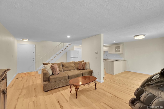 2840 S Kenton Ct, Aurora, CO 80014 - living room featuring a textured ceiling, light wood finished floors, stairs, and baseboards