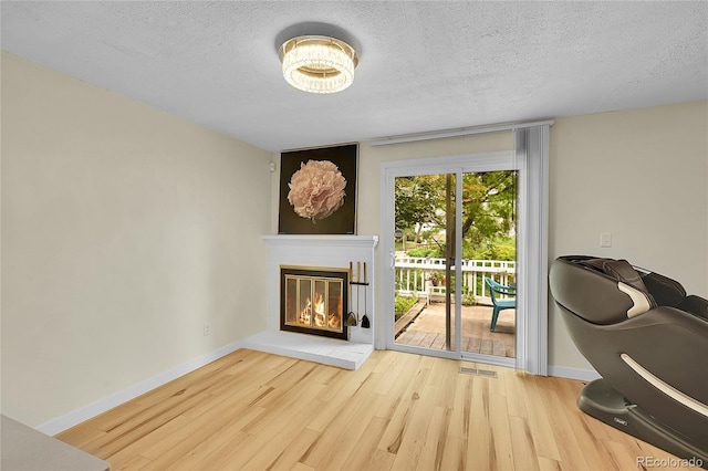 2840 S Kenton Ct, Aurora, CO 80014 - living area featuring wood finished floors, a glass covered fireplace, a textured ceiling, and baseboards
