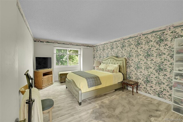 2840 S Kenton Ct, Aurora, CO 80014 - bedroom featuring a textured ceiling, baseboards, wallpapered walls, and wood finished floors