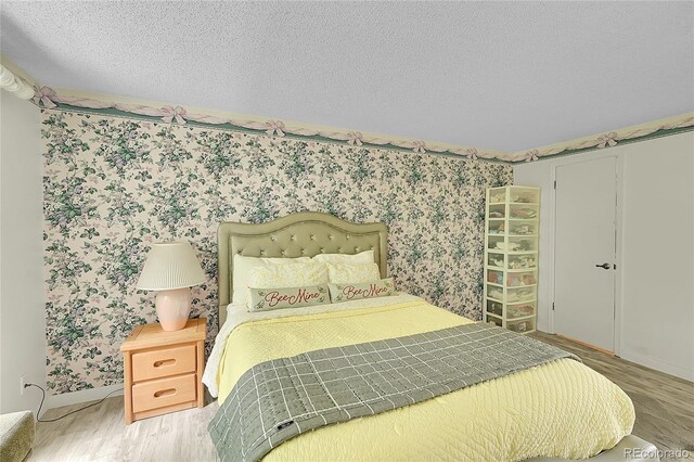 2840 S Kenton Ct, Aurora, CO 80014 - bedroom featuring wood finished floors, baseboards, wallpapered walls, and a textured ceiling