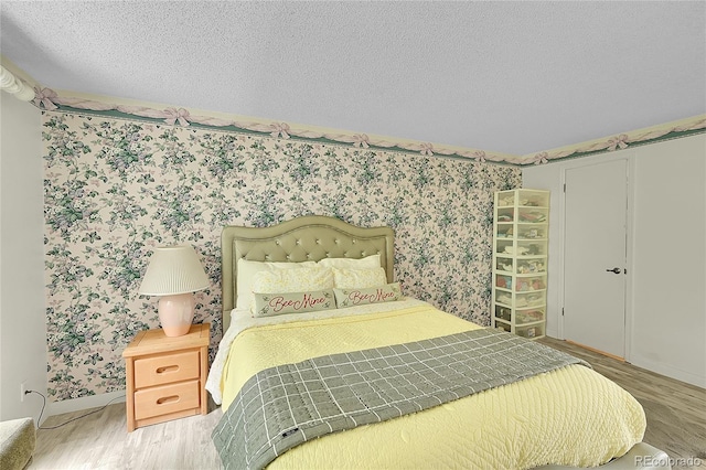 2840 S Kenton Ct, Aurora, CO 80014 - bedroom featuring wood finished floors, wallpapered walls, and a textured ceiling