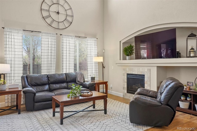 15960 W 62nd Dr, Arvada, CO 80403 - living area with a tile fireplace, wood finished floors, baseboards, and a high ceiling