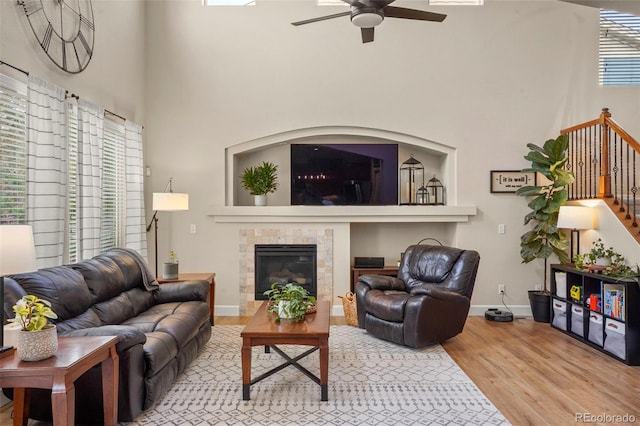 15960 W 62nd Dr, Arvada, CO 80403 - living room with wood finished floors, stairway, ceiling fan, a high ceiling, and a tile fireplace