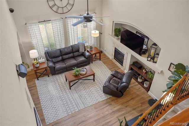 15960 W 62nd Dr, Arvada, CO 80403 - living area featuring wood finished floors, a ceiling fan, a fireplace, baseboards, and a towering ceiling