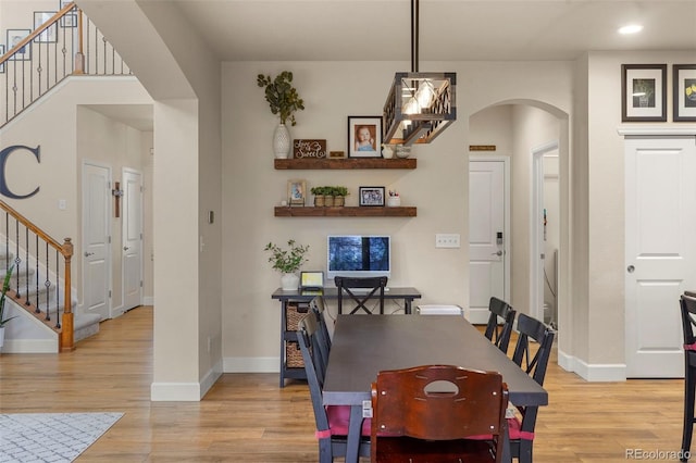 15960 W 62nd Dr, Arvada, CO 80403 - dining space with stairway, arched walkways, light wood-type flooring, and baseboards