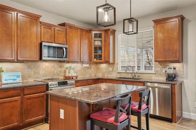 15960 W 62nd Dr, Arvada, CO 80403 - kitchen with a kitchen bar, a sink, brown cabinetry, light wood-type flooring, and appliances with stainless steel finishes