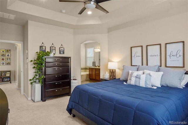 15960 W 62nd Dr, Arvada, CO 80403 - bedroom featuring a tray ceiling, visible vents, arched walkways, ensuite bath, and light carpet