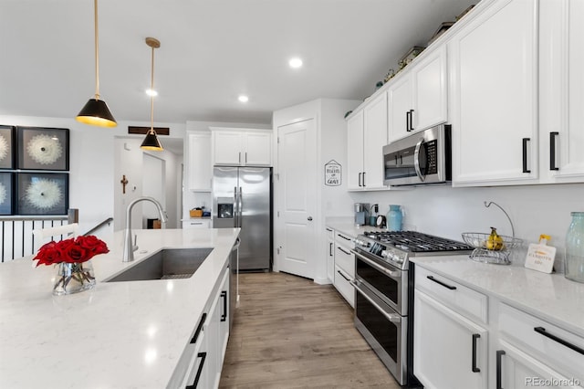 kitchen featuring appliances with stainless steel finishes, light hardwood / wood-style flooring, light stone counters, and sink