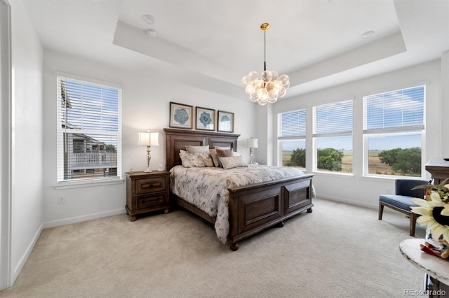 bedroom with an inviting chandelier, a tray ceiling, and light colored carpet