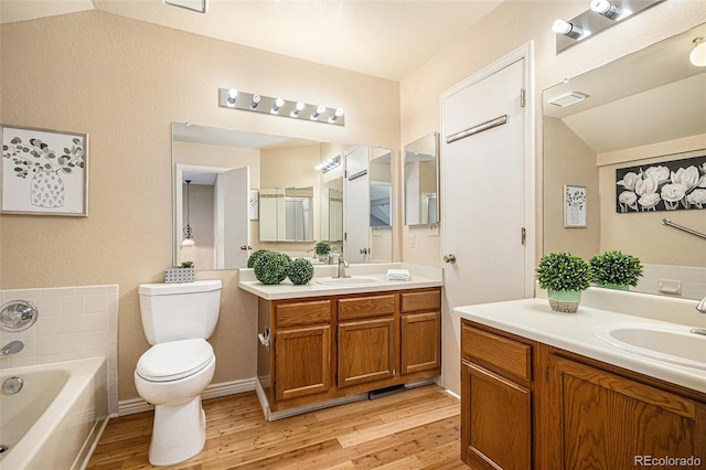 bathroom featuring hardwood / wood-style floors, lofted ceiling, vanity, and toilet