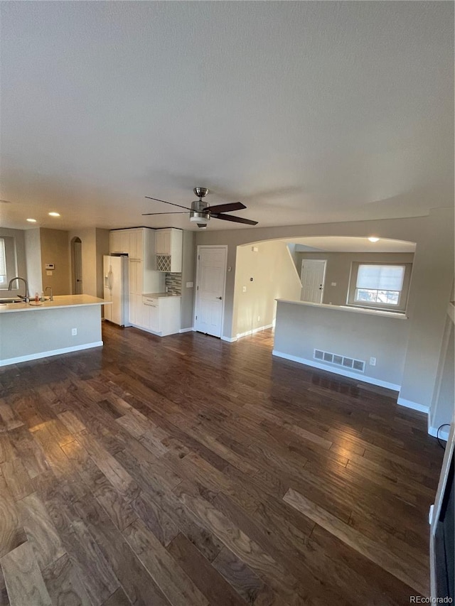 unfurnished living room featuring sink, ceiling fan, and dark wood-type flooring