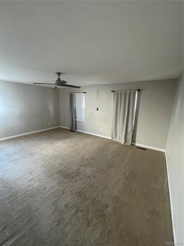 spare room with ceiling fan and dark colored carpet