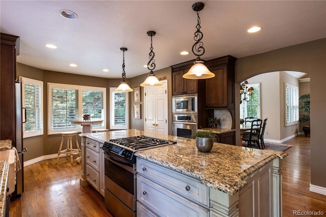9 Roder Gate Ln, Castle Pines, CO 80108 - kitchen with appliances with stainless steel finishes, baseboards, arched walkways, dark wood-style floors, and recessed lighting