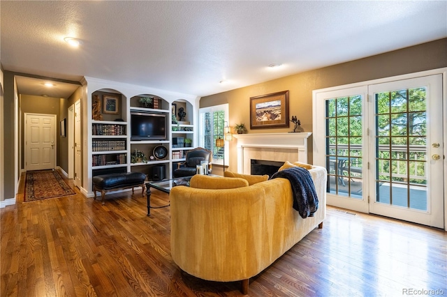 9 Roder Gate Ln, Castle Pines, CO 80108 - living room with a fireplace, dark wood finished floors, built in shelves, and baseboards