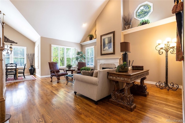 9 Roder Gate Ln, Castle Pines, CO 80108 - living room with high vaulted ceiling, a fireplace, baseboards, wood finished floors, and a chandelier