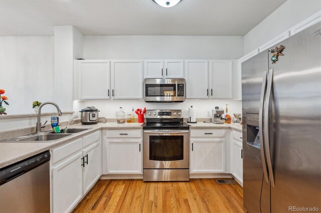 178 Blue Bonnet Dr, Brighton, CO 80601 - kitchen with appliances with stainless steel finishes, a sink, white cabinetry, and light wood-type flooring