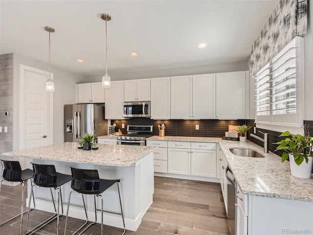 kitchen featuring appliances with stainless steel finishes, decorative light fixtures, white cabinetry, and sink