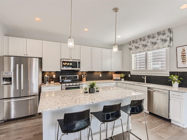 kitchen featuring pendant lighting, a center island, white cabinets, sink, and appliances with stainless steel finishes